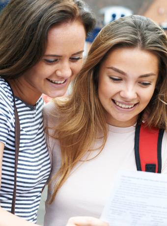 Two girls looking at page containing exam results